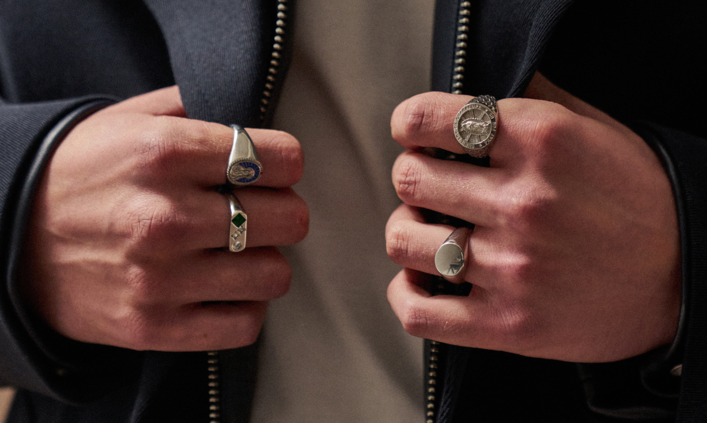 Man wearing different styles of silver band and signet rings