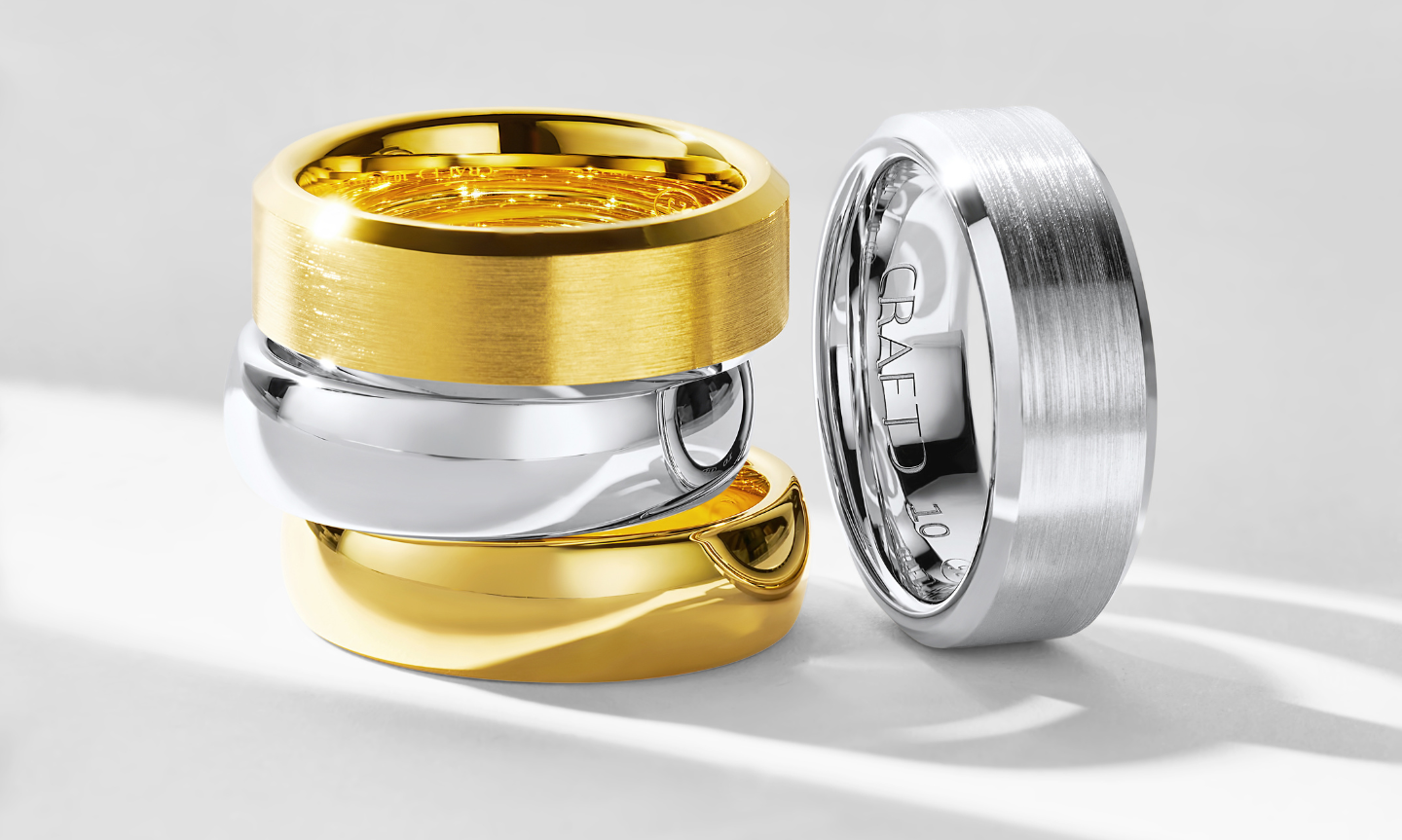 A stack of 4 different gold and silver men's wedding bands each stacked on of each other