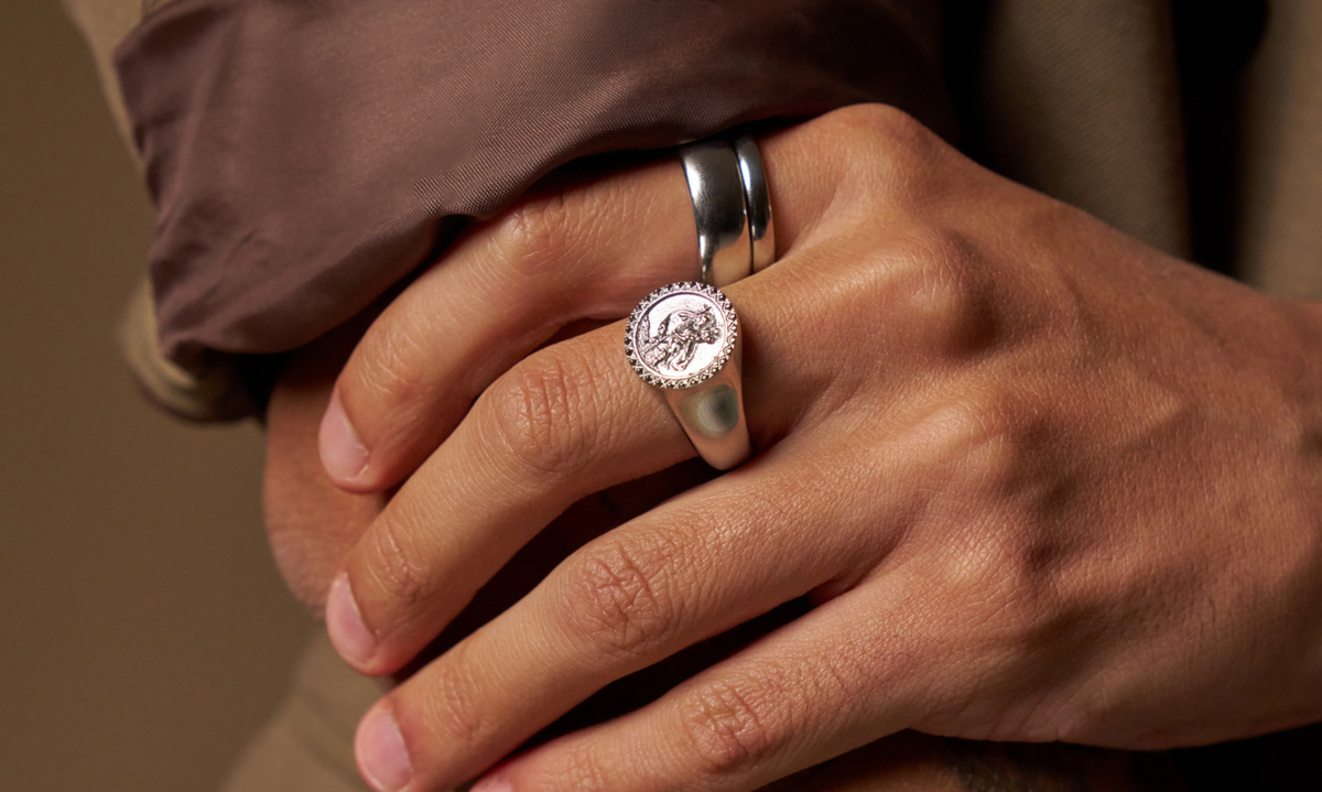 Man's hand wearing a tungsten and titanium wedding band in silver