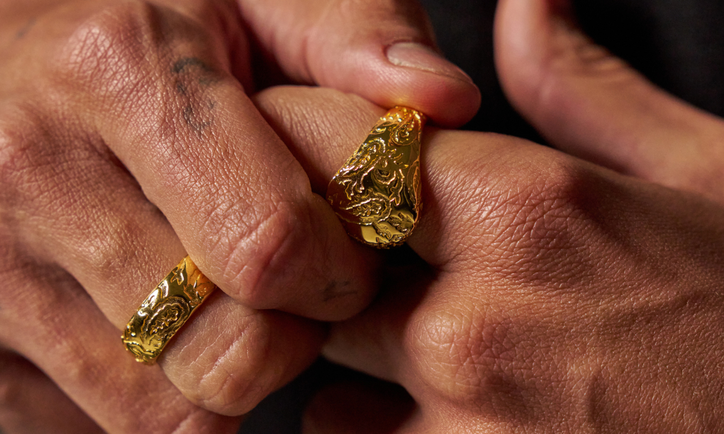 Man's hand wearing a gold plated tungsten wedding band