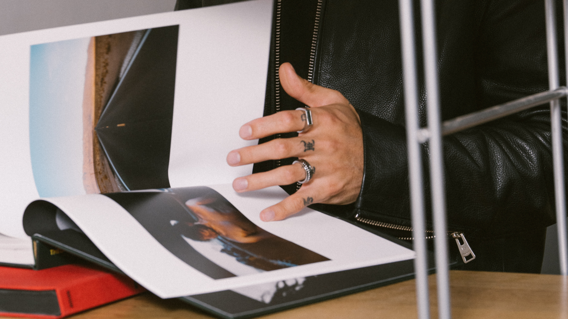 Man flicking through a jewellery style guide catalogue. He's wearing silver rings. 